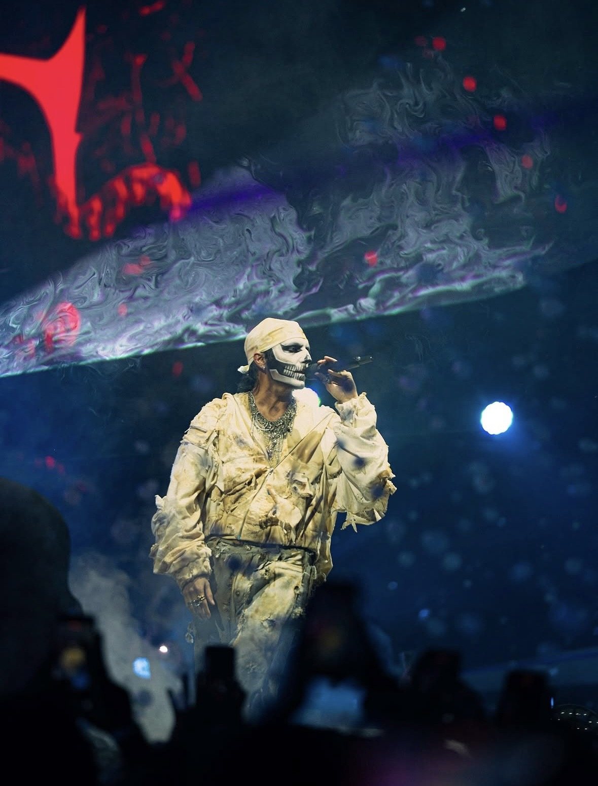 Performer above the crowd in red light and smoke