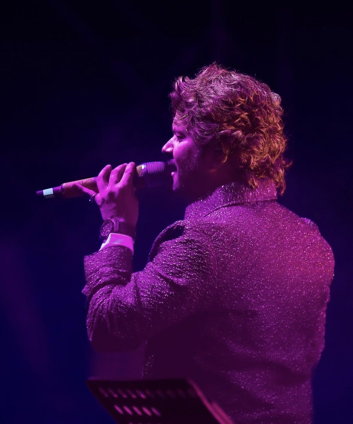 Singer in purple light holding a microphone